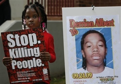 Nadashia Thomas, 6, a cousin of Derrion Albert, holds a sign beside a poster of  Derrion Albert at Fenger High School  in Chicago, Sept. 28, 2009. A vigil for Derrion Albert was planned outside of  Fenger High School. (AP Photo/Nam Y. Huh)
